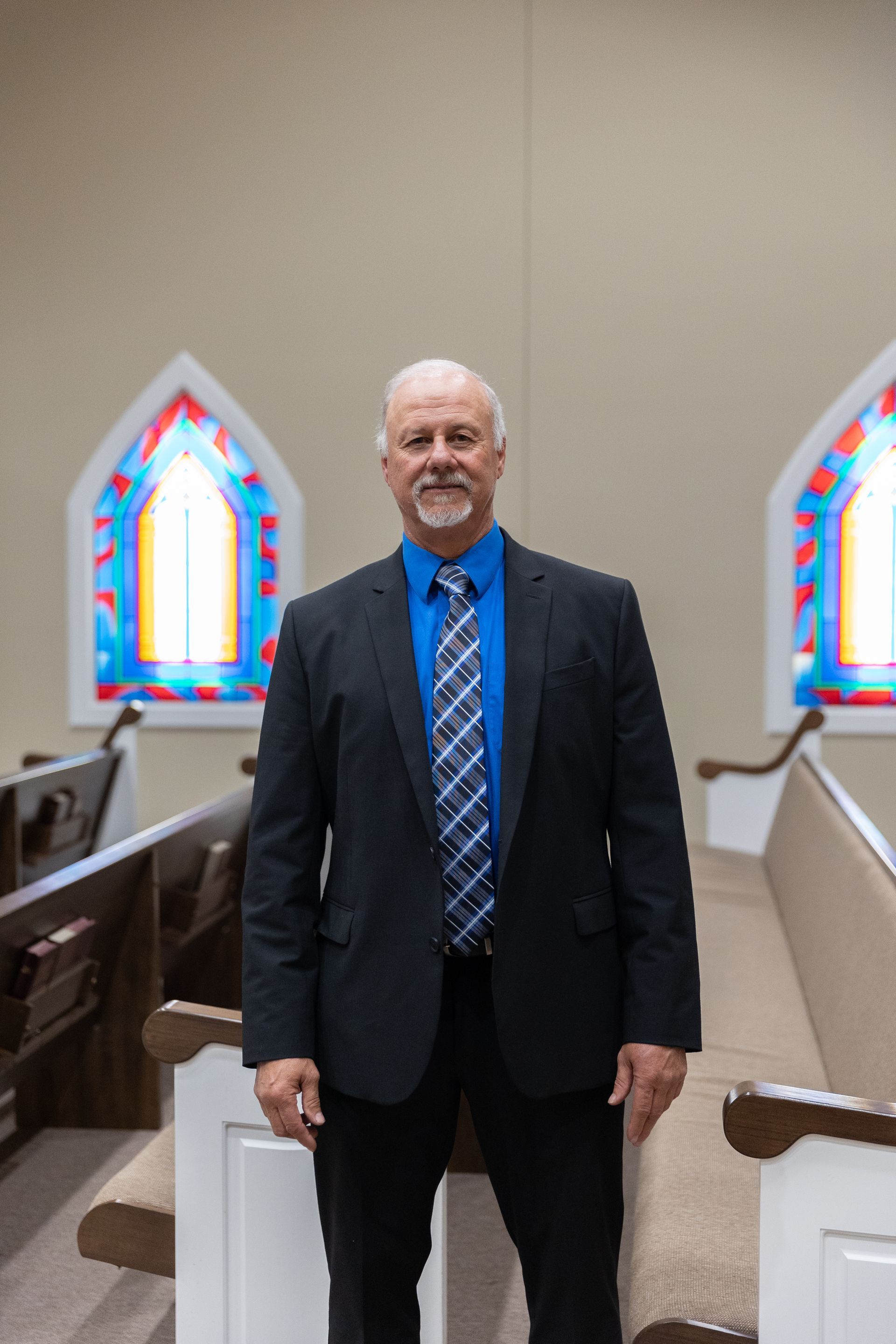 A man with a beard is wearing a plaid shirt and tie.