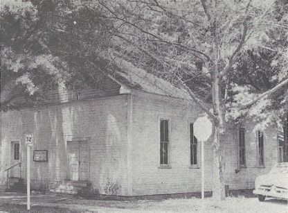 A black and white photo of a building with trees in front of it