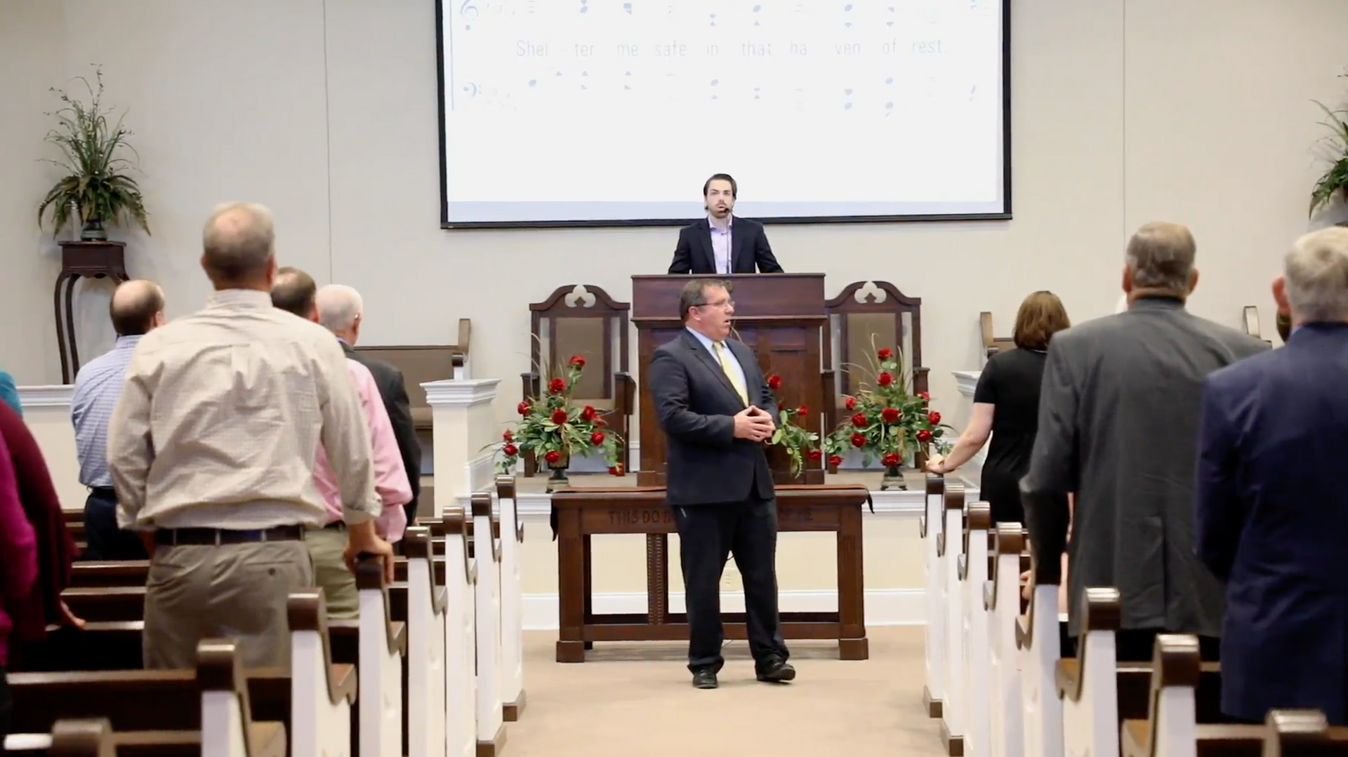 A man is standing at a podium in front of a group of people in a church.