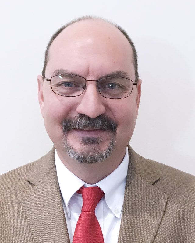 A man with a beard wearing a blue shirt and tie