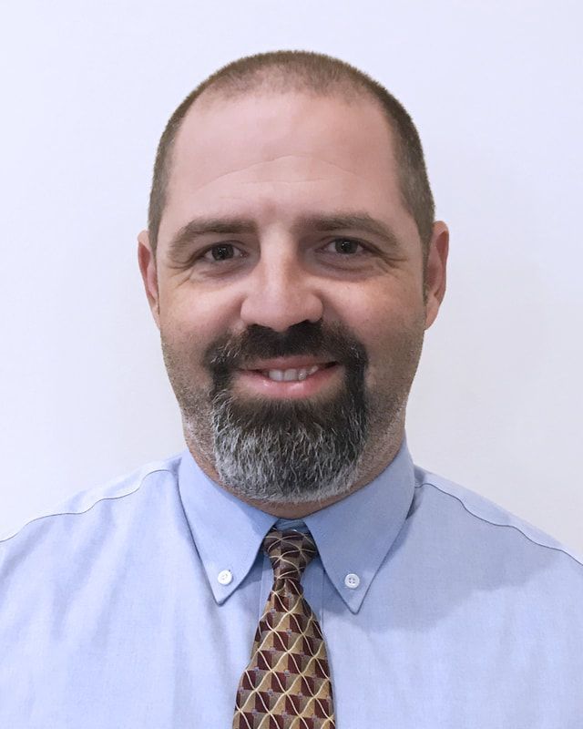 A man in a suit and tie is smiling for the camera