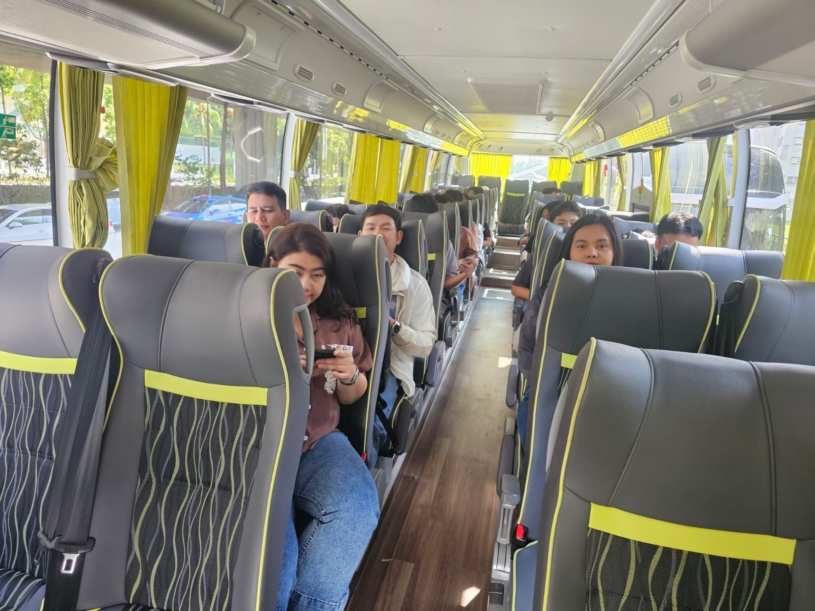 Inside a bus with several young people sitting in the seats, looking at phones or forward.