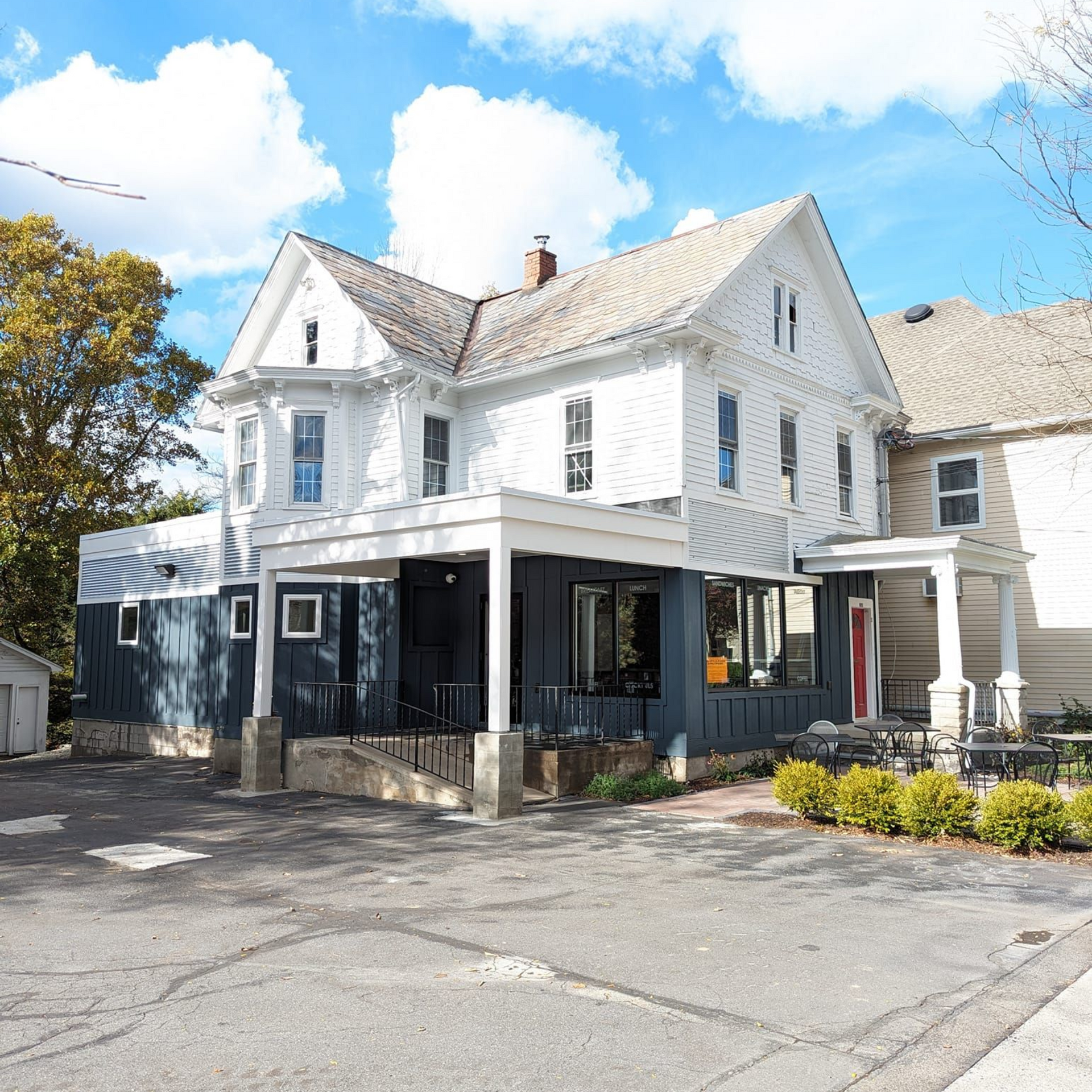 White house with dark blue ground floor, porch, and blue sky.