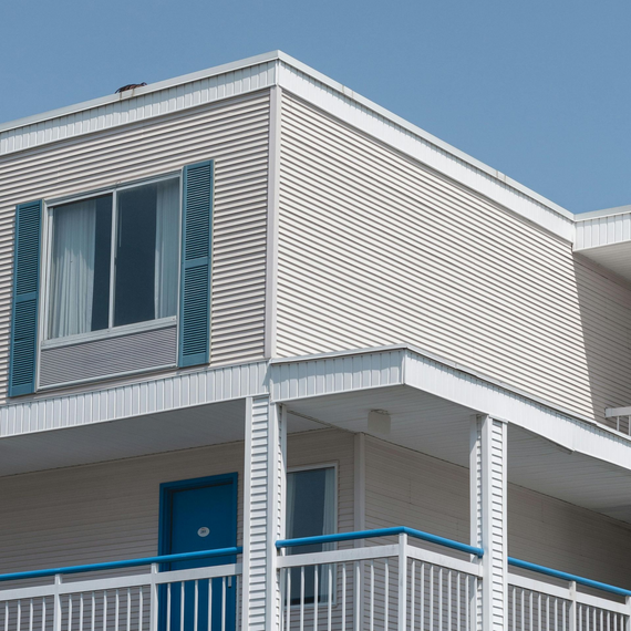 Motel building exterior with blue doors, shutters, and railings against a clear blue sky.