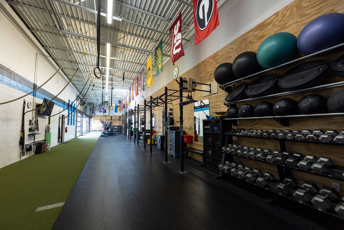 A gym with a lot of dumbbells and balls on shelves.