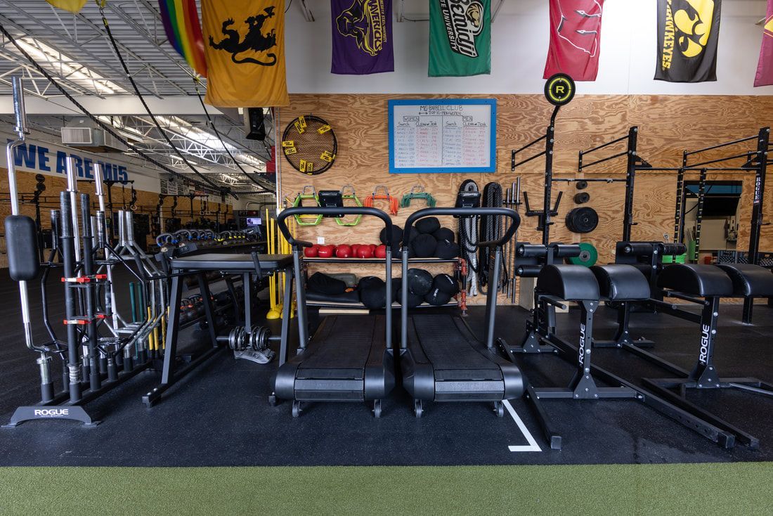 A gym with a lot of equipment and flags on the wall.