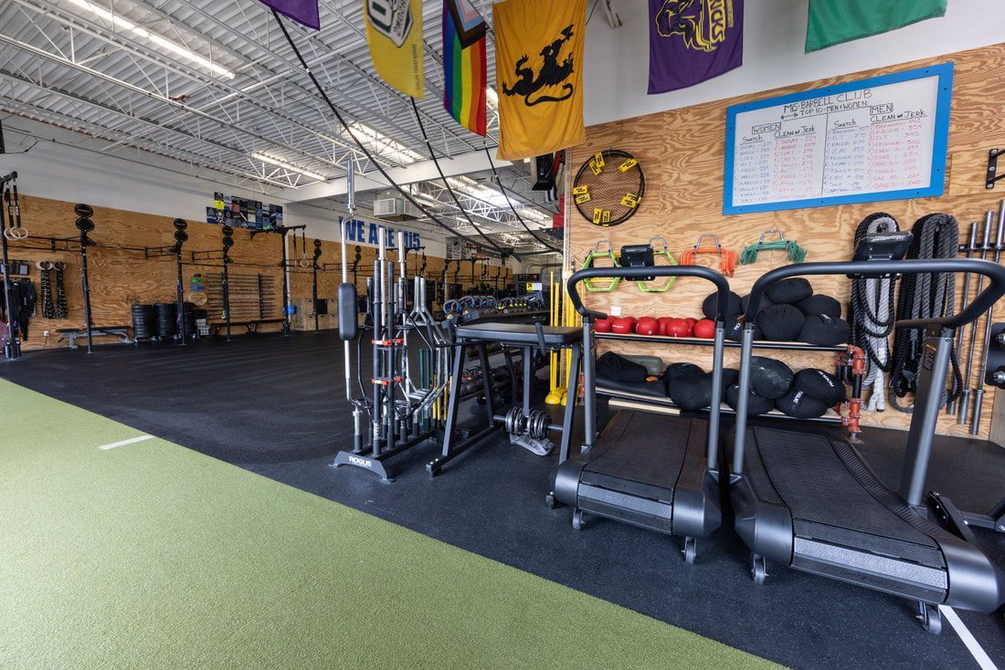 A gym with a treadmill and a bunch of flags on the wall.