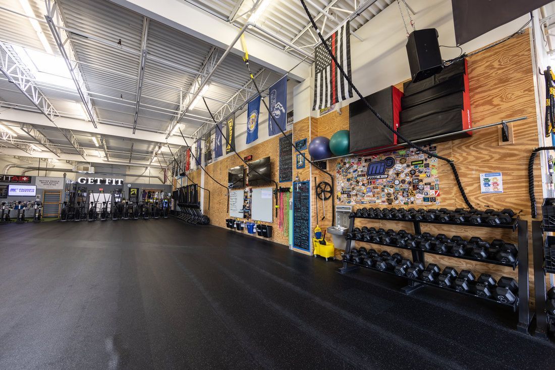 A large gym with a lot of dumbbells and a lot of flags on the wall.