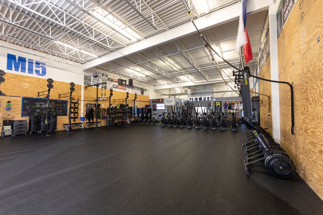 A large gym with a lot of equipment and a flag on the wall.