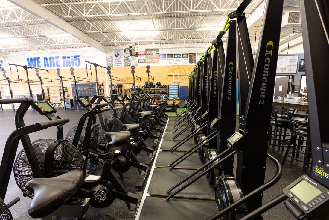 A row of exercise bikes are lined up in a gym.