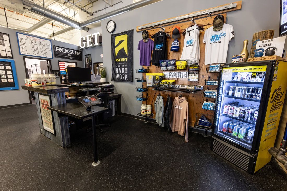 The inside of a gym with a counter and a refrigerator.