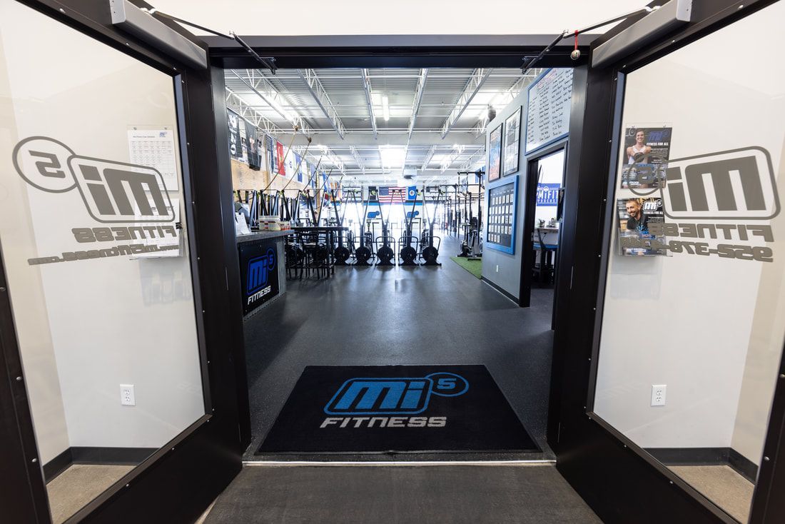 A gym with two doors open and a mat on the floor.