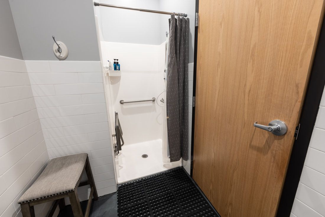 A bathroom with a walk in shower and a wooden door.
