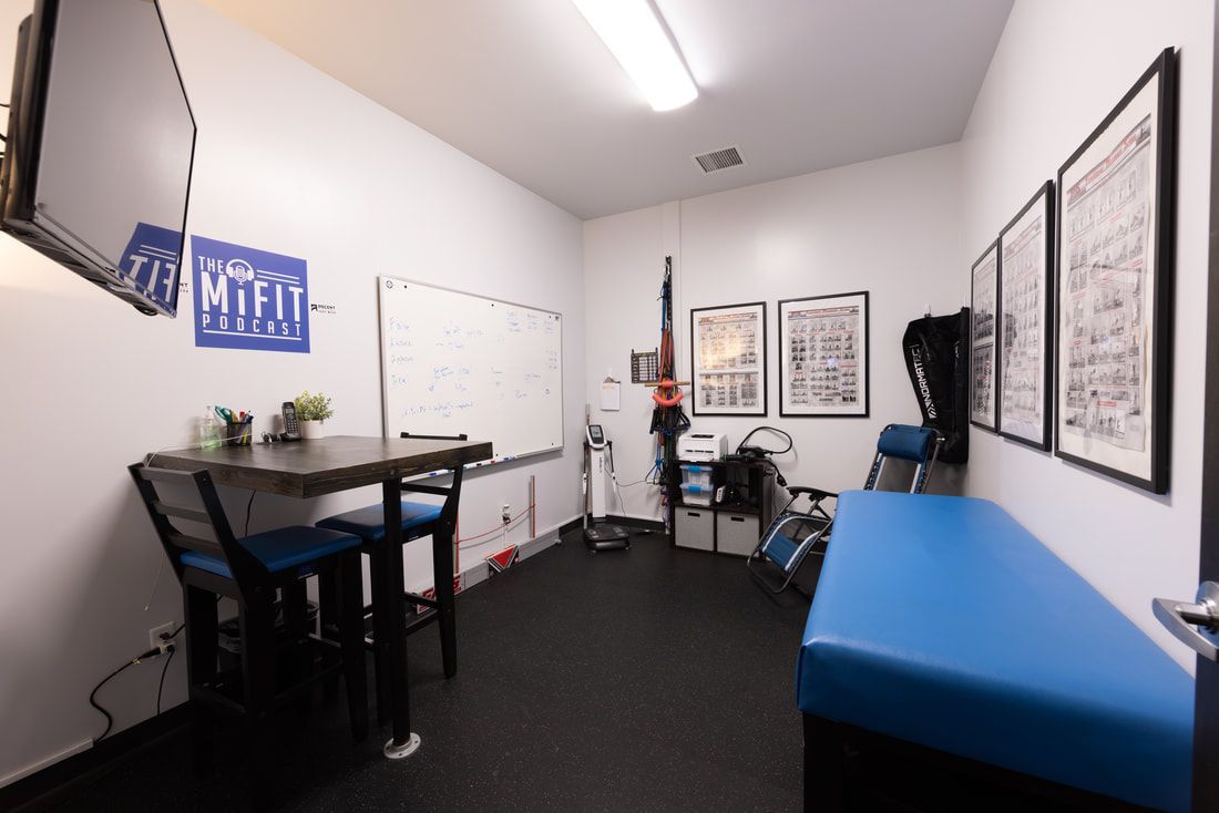 A room with a table and chairs and a whiteboard on the wall.