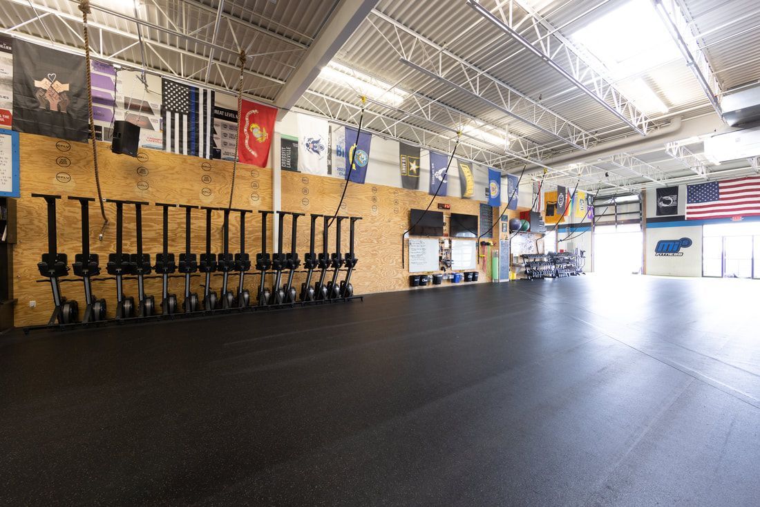 A large gym with a lot of weights and flags on the wall.