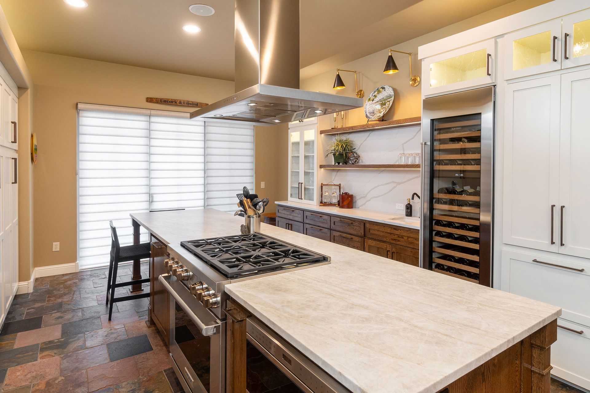 A kitchen with a large island , stove , refrigerator and stainless steel appliances.
