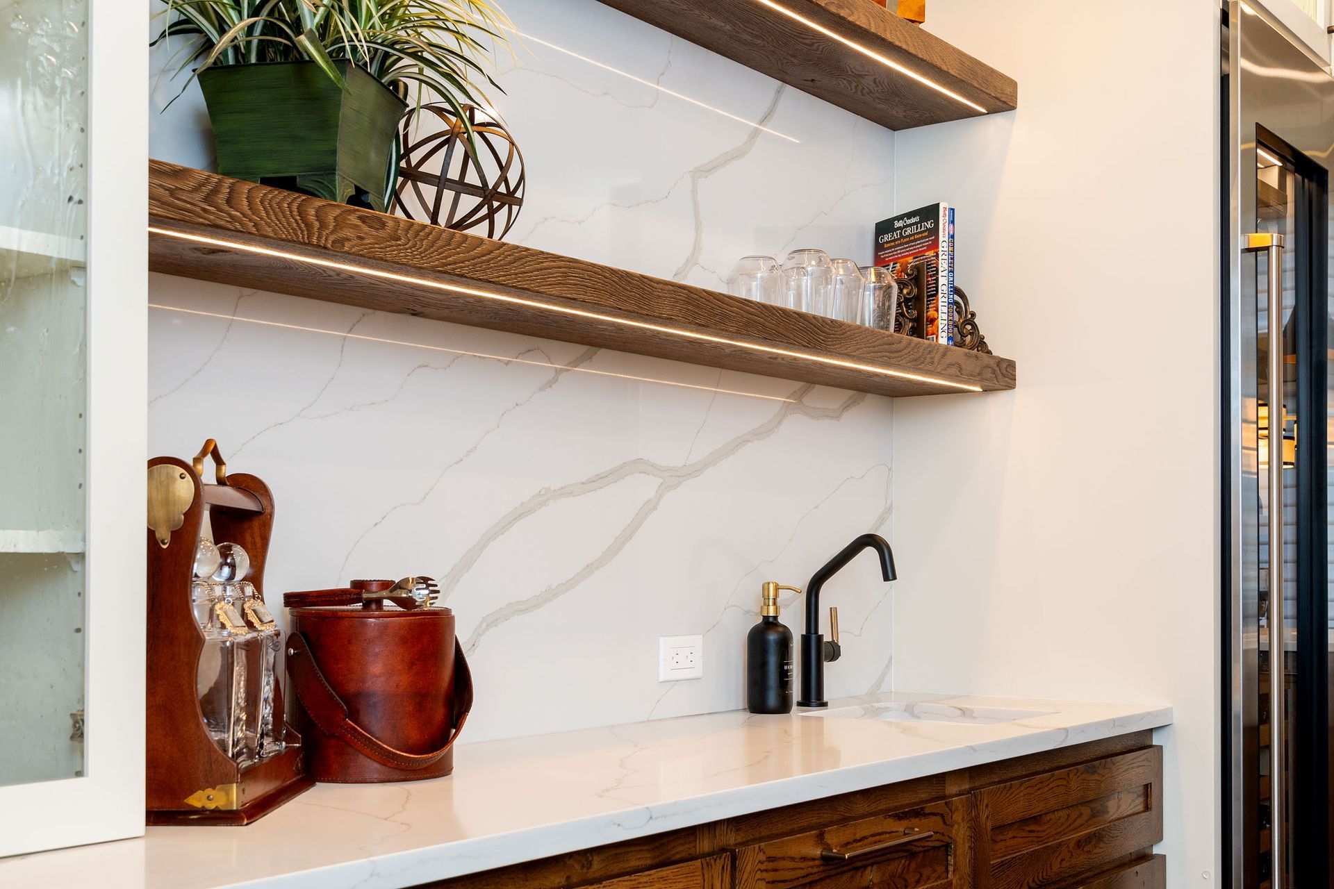A kitchen with a sink , ice bucket , and shelves.