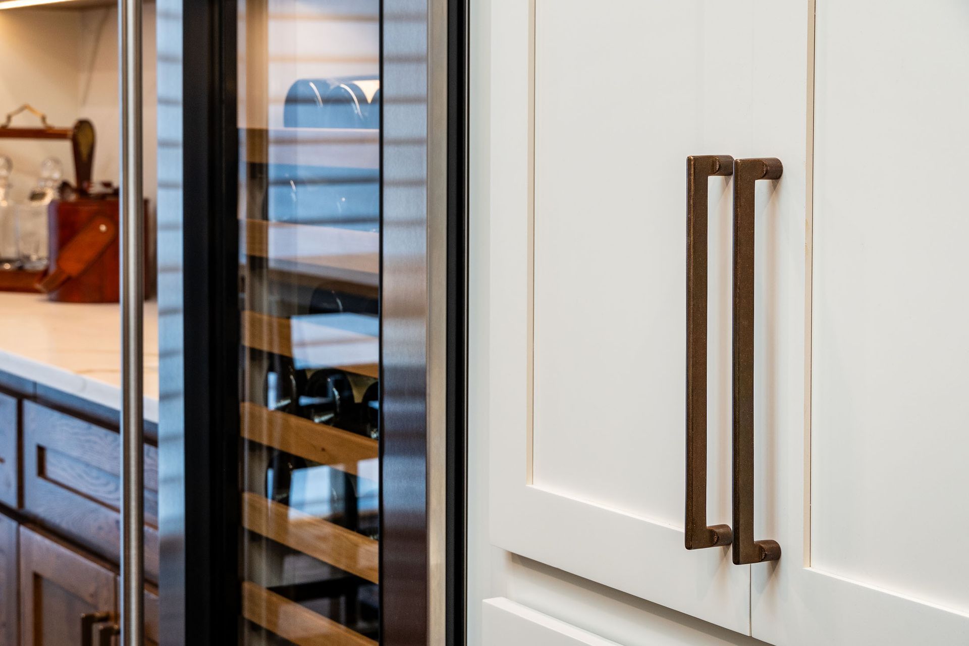 There is a wine cooler in the kitchen with a glass door.