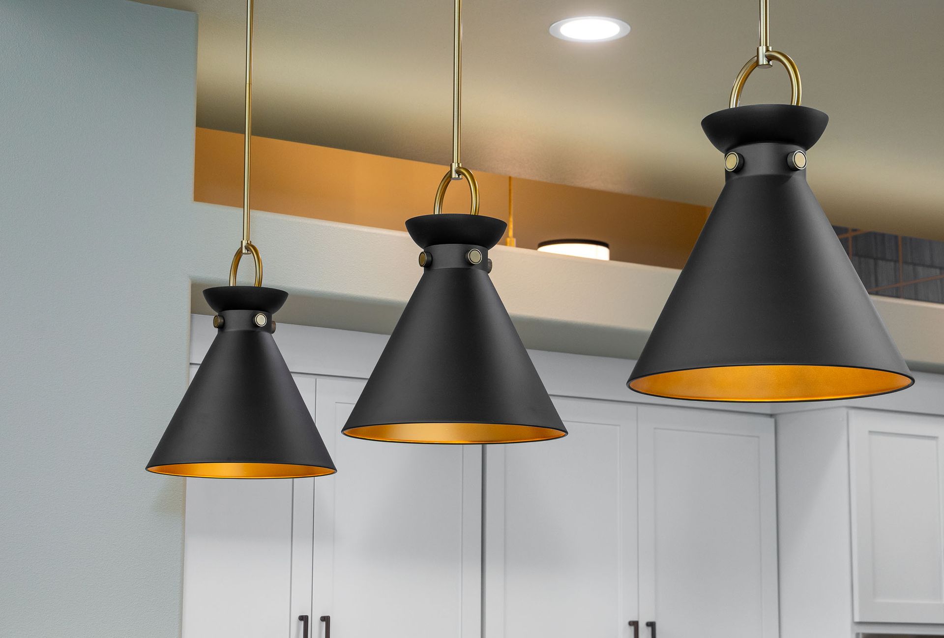 Three black pendant lights are hanging from the ceiling in a kitchen