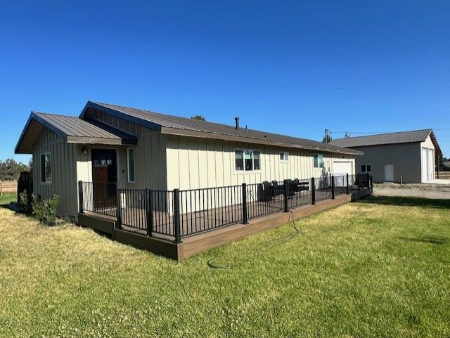 A house with a deck and a fence in front of it.