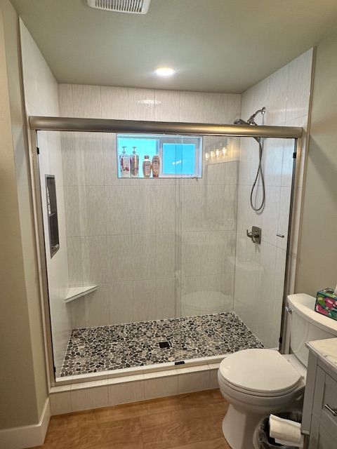 A bathroom with a toilet and a shower with a glass door.