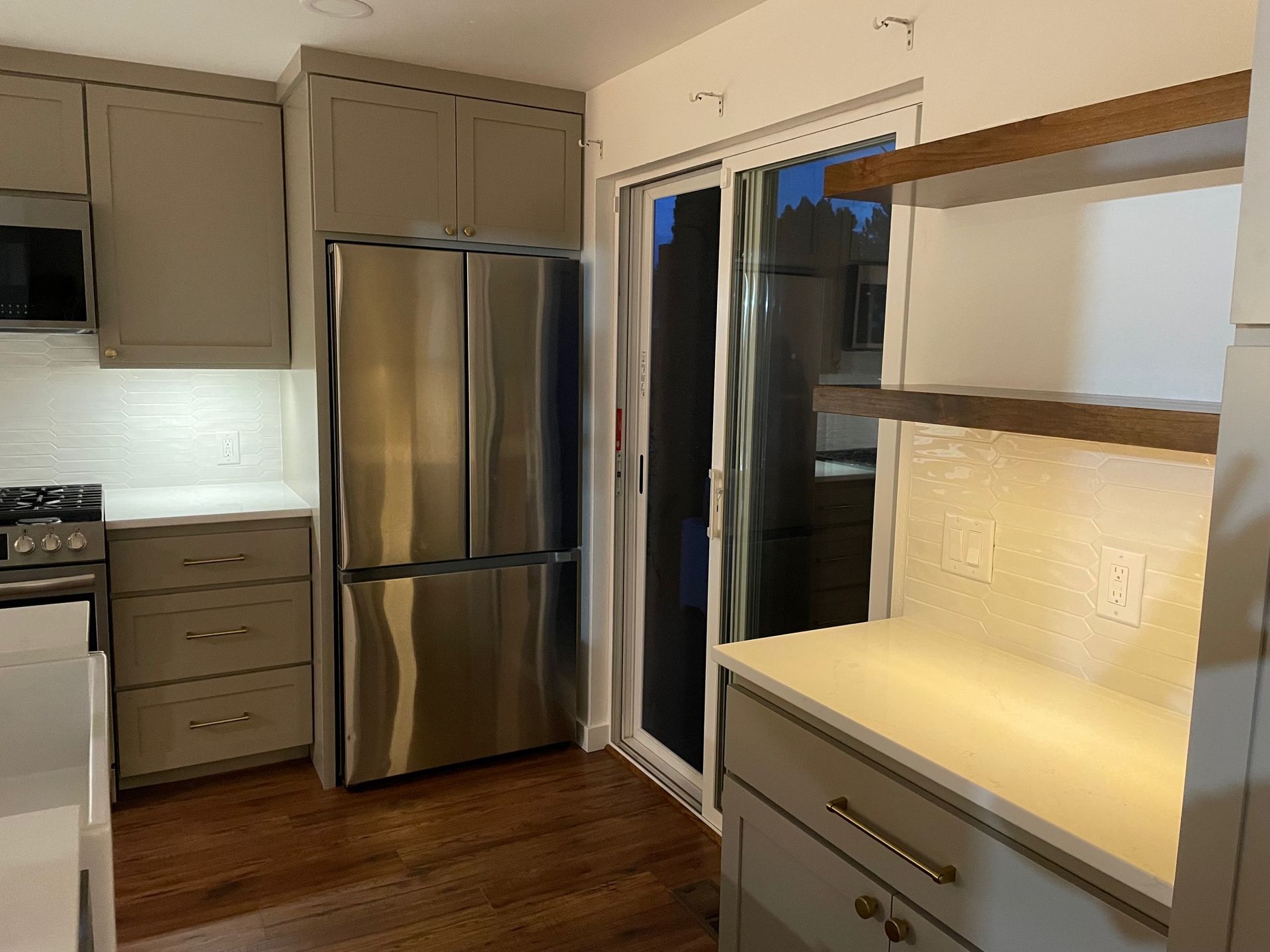 A kitchen with stainless steel appliances and a sliding glass door
