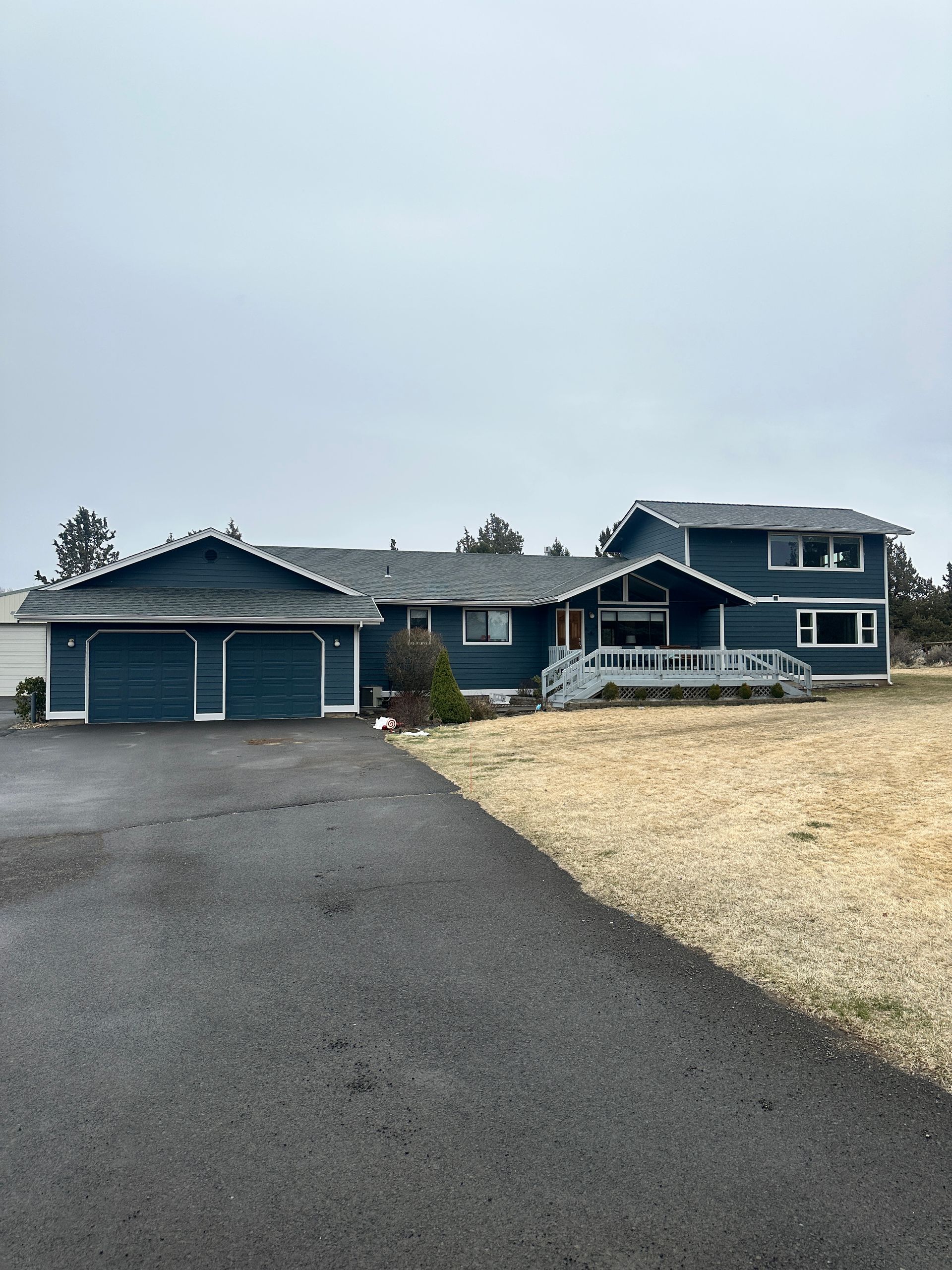 A large blue house with a driveway in front of it.