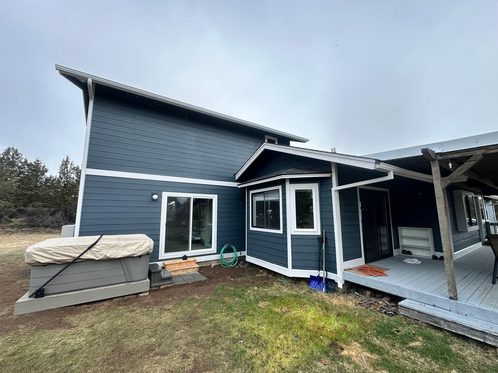 A large blue house with a hot tub in the backyard.