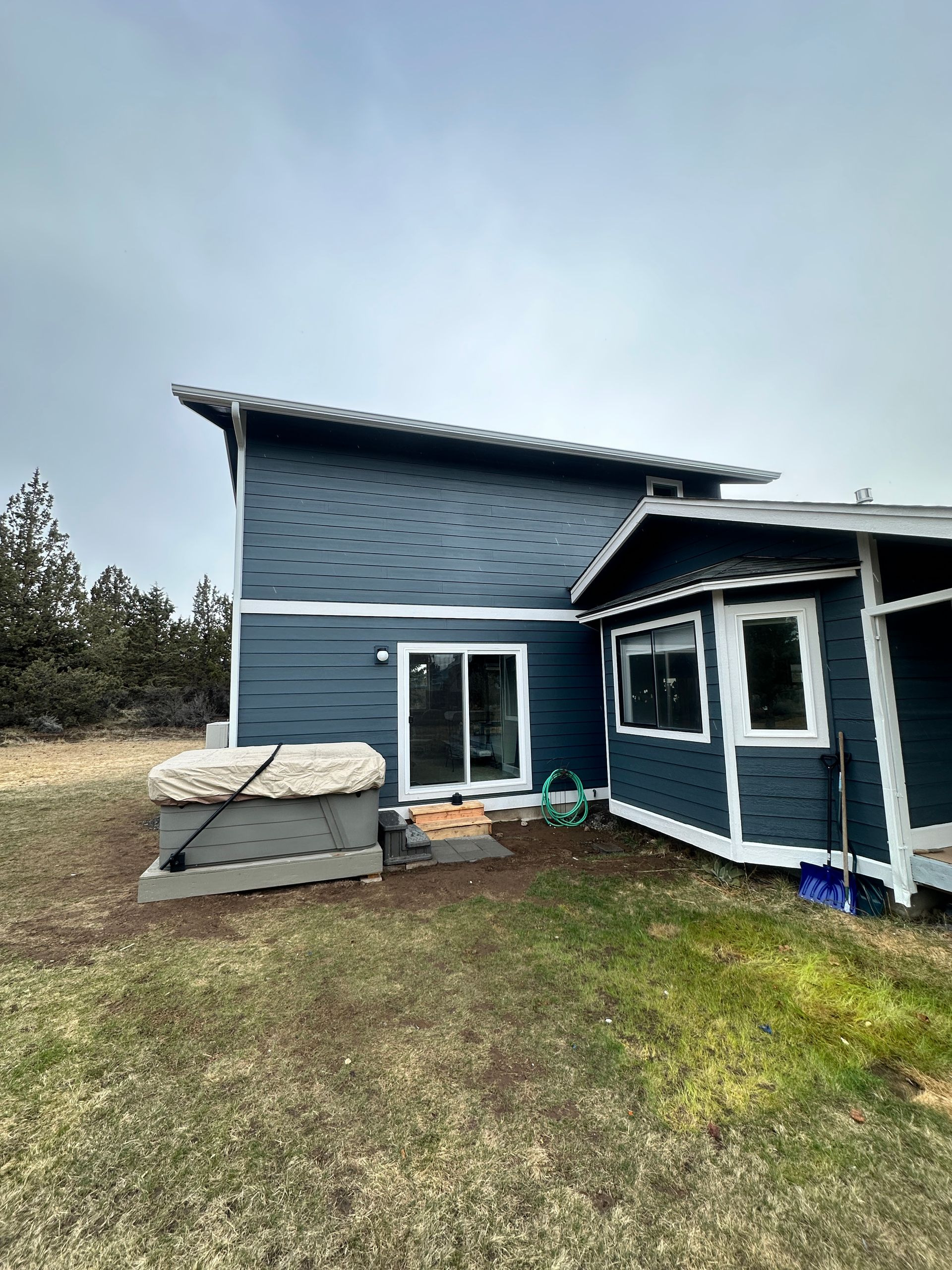 A blue house with a hot tub in the backyard.