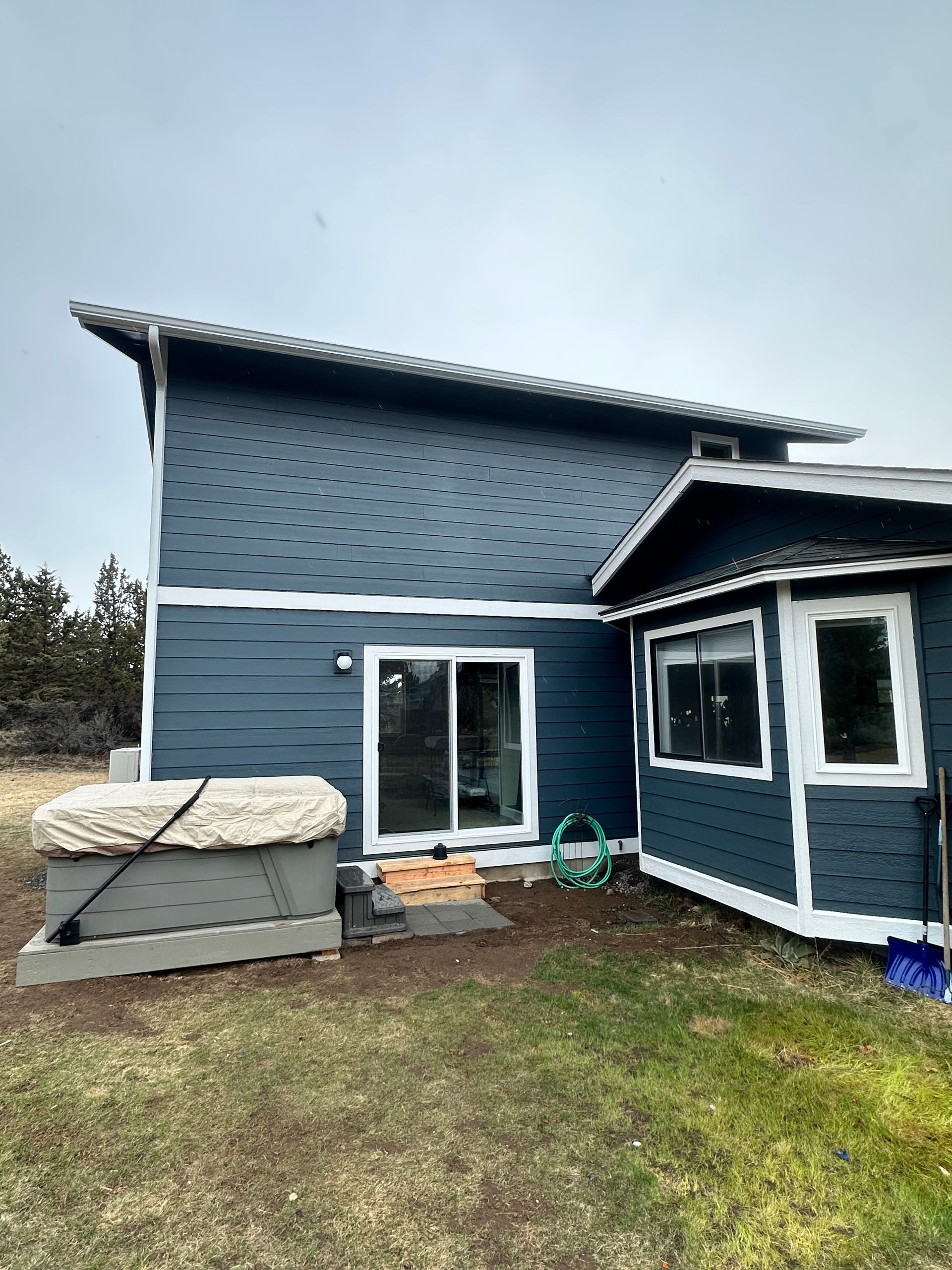 A blue house with a hot tub in the backyard.