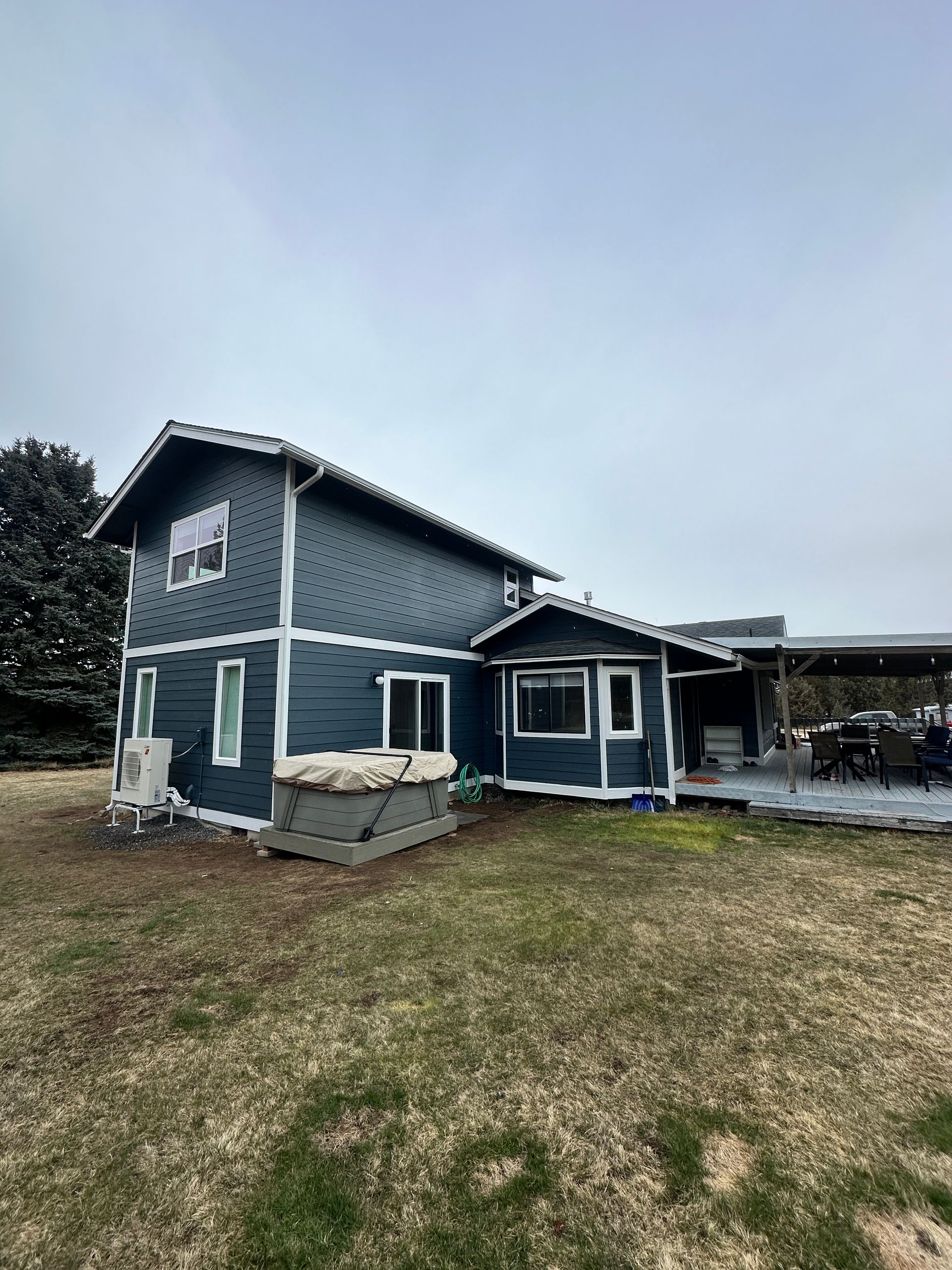 A large blue house is sitting in the middle of a grassy field.