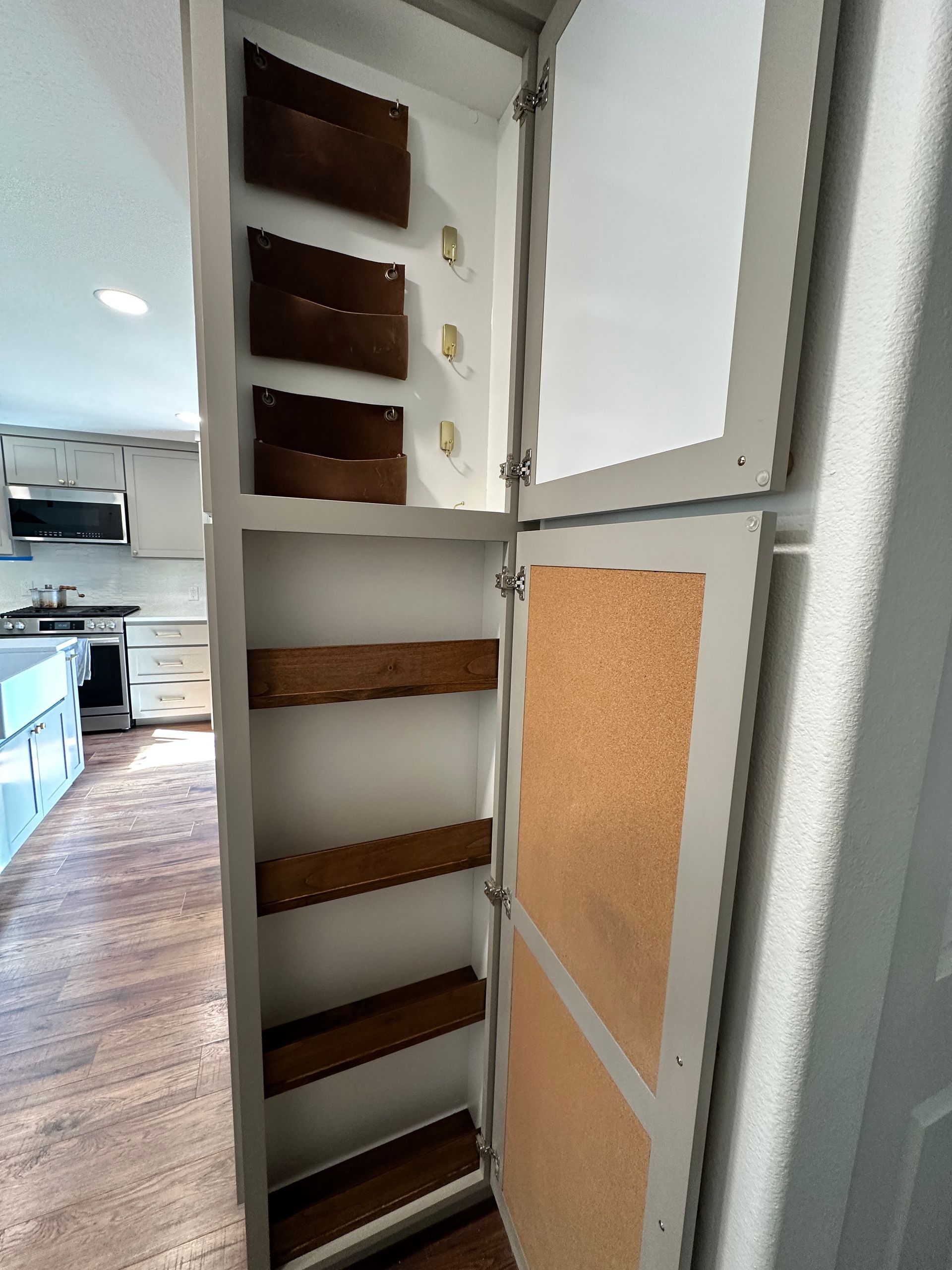 A cabinet with a cork door and wooden shelves in a kitchen.