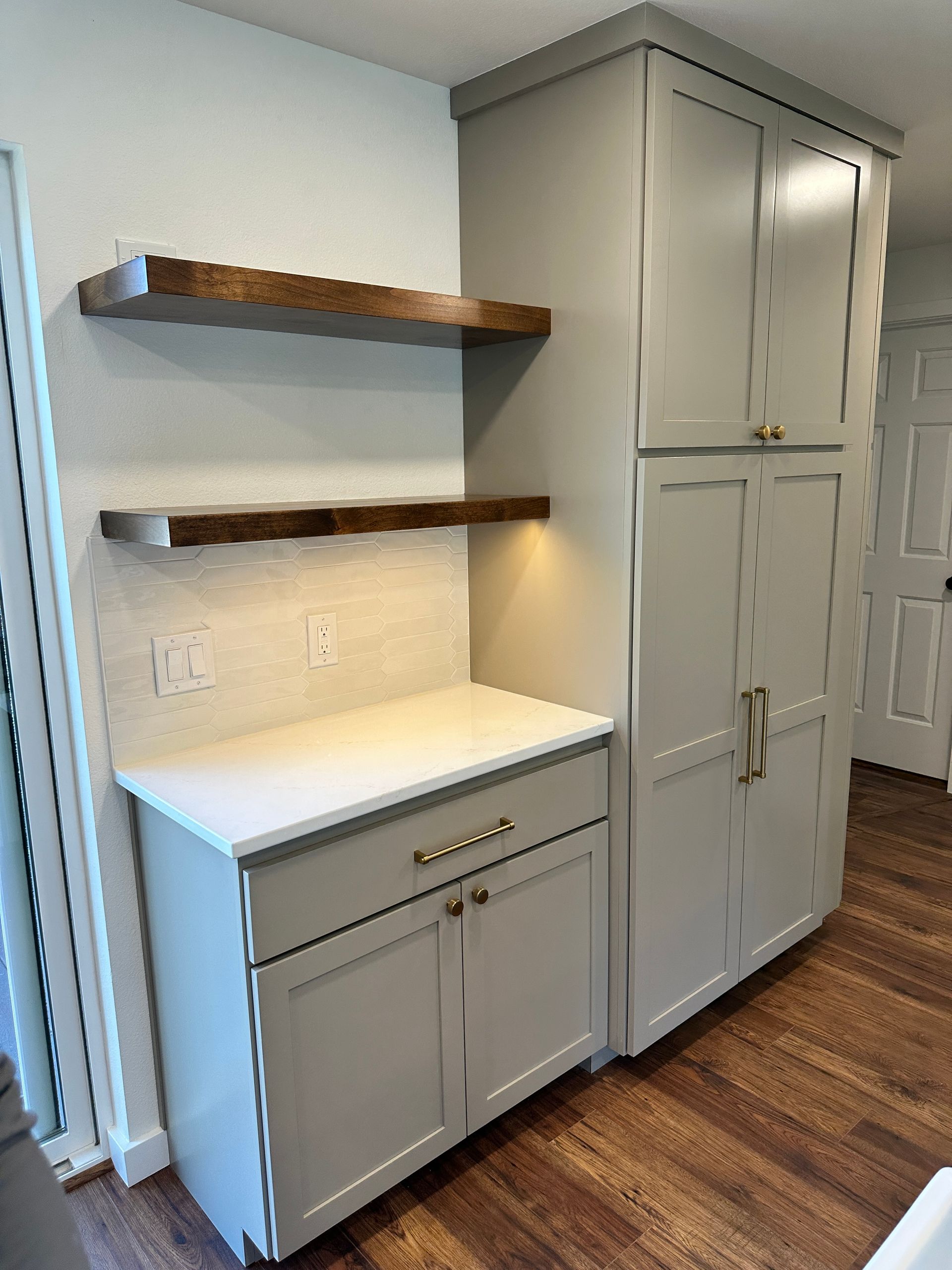 A kitchen with gray cabinets and wooden shelves.