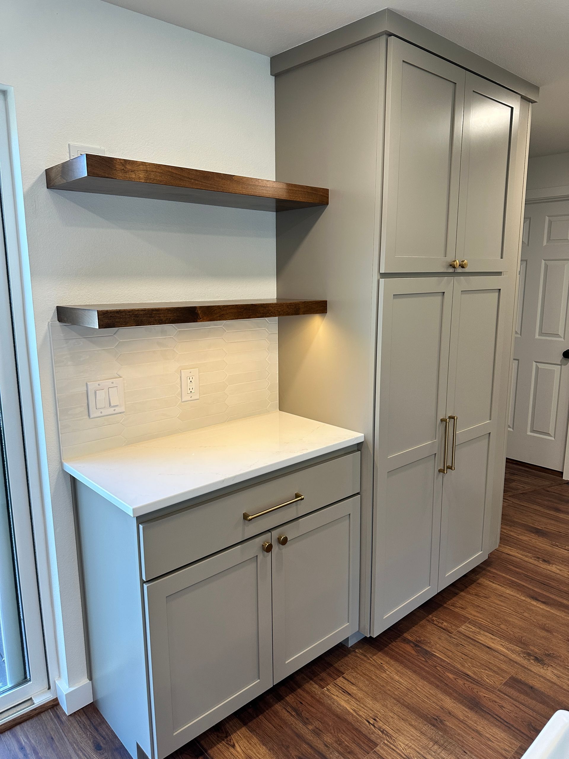 A kitchen with white cabinets and wooden shelves.