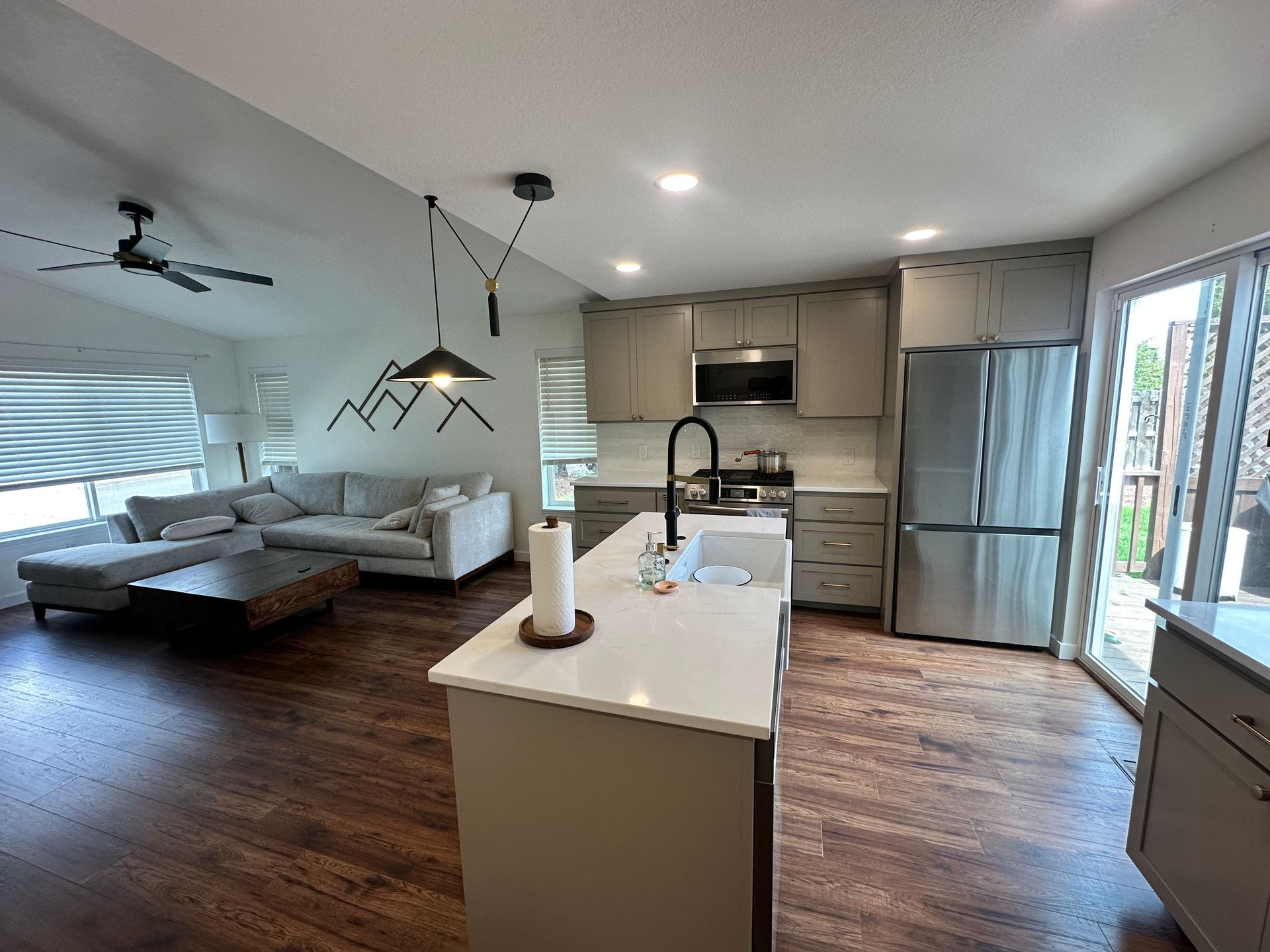 A living room with a couch and a kitchen with stainless steel appliances.