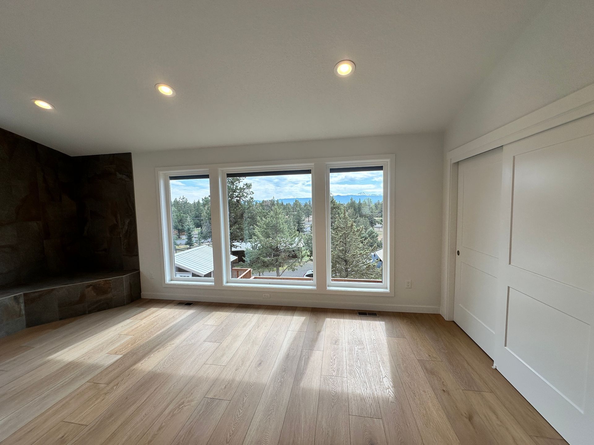 An empty living room with hardwood floors and lots of windows.