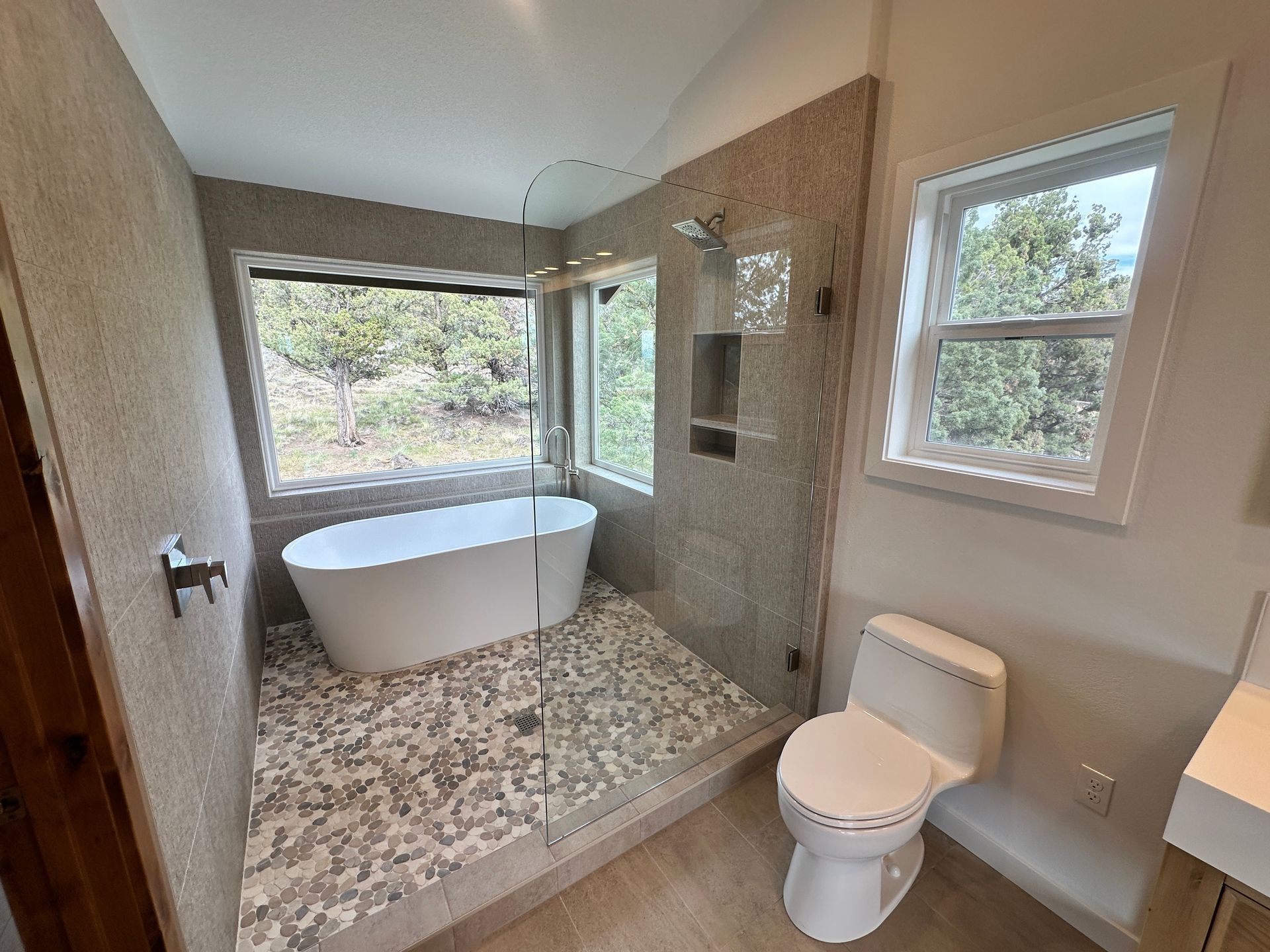 A bathroom with a tub , toilet , sink and window.