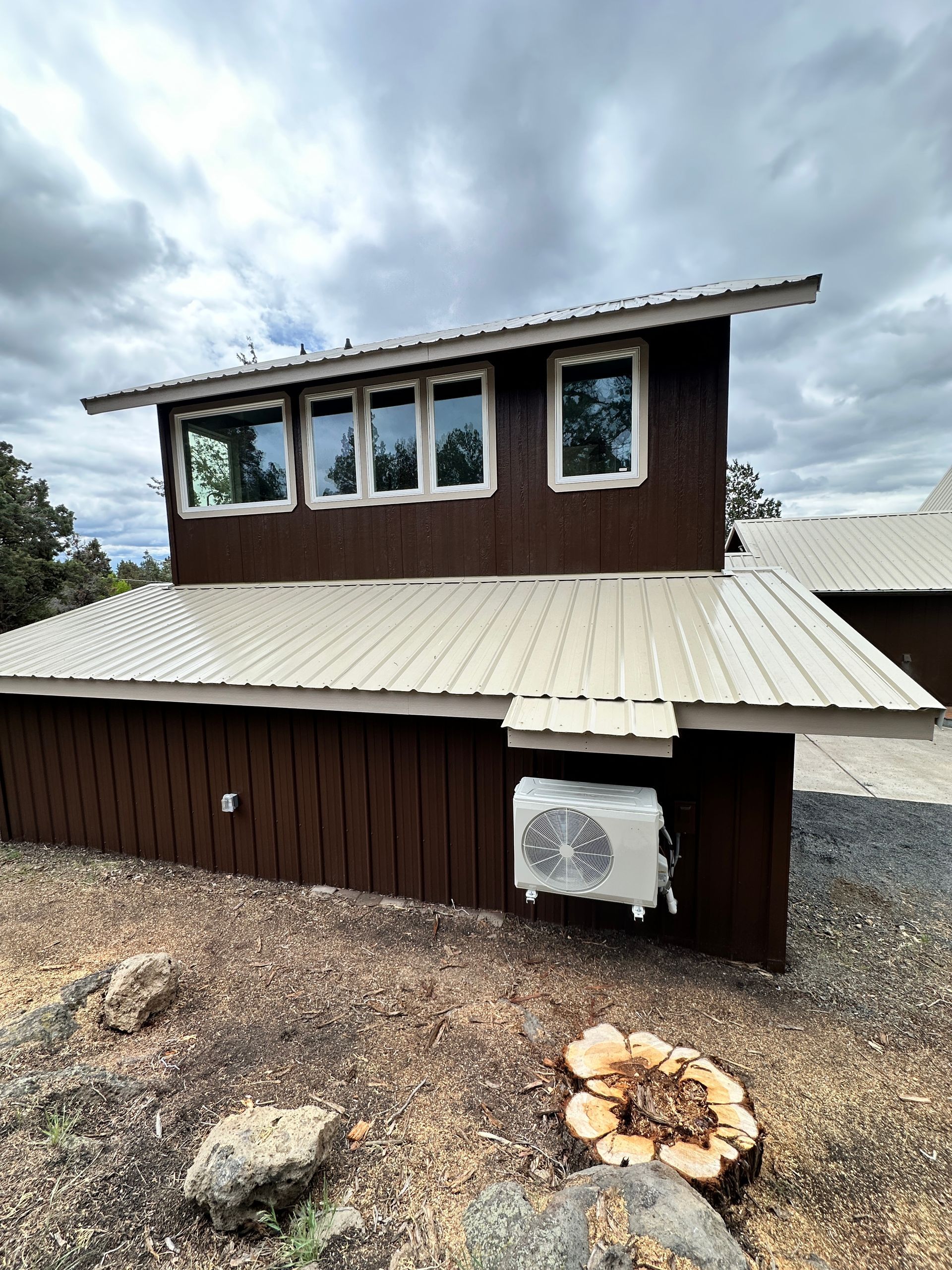 A brown house with a white roof and a few windows
