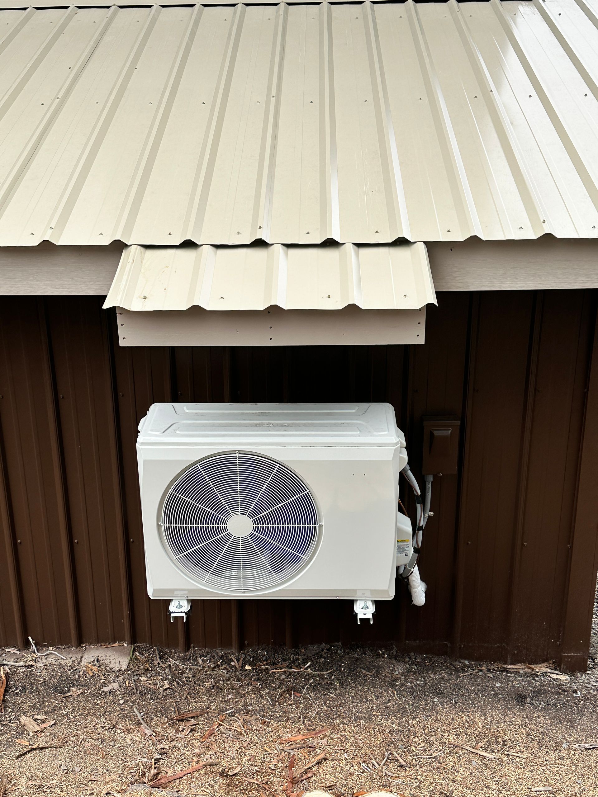 A white air conditioner is hanging from the side of a building.