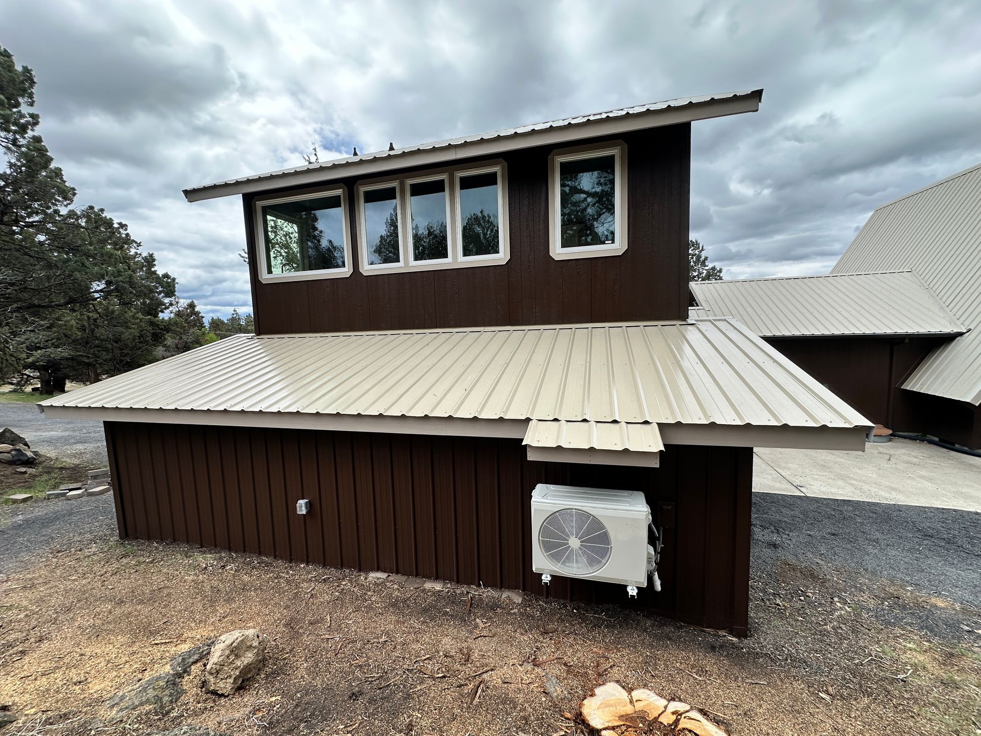 A brown house with a metal roof and a white air conditioner