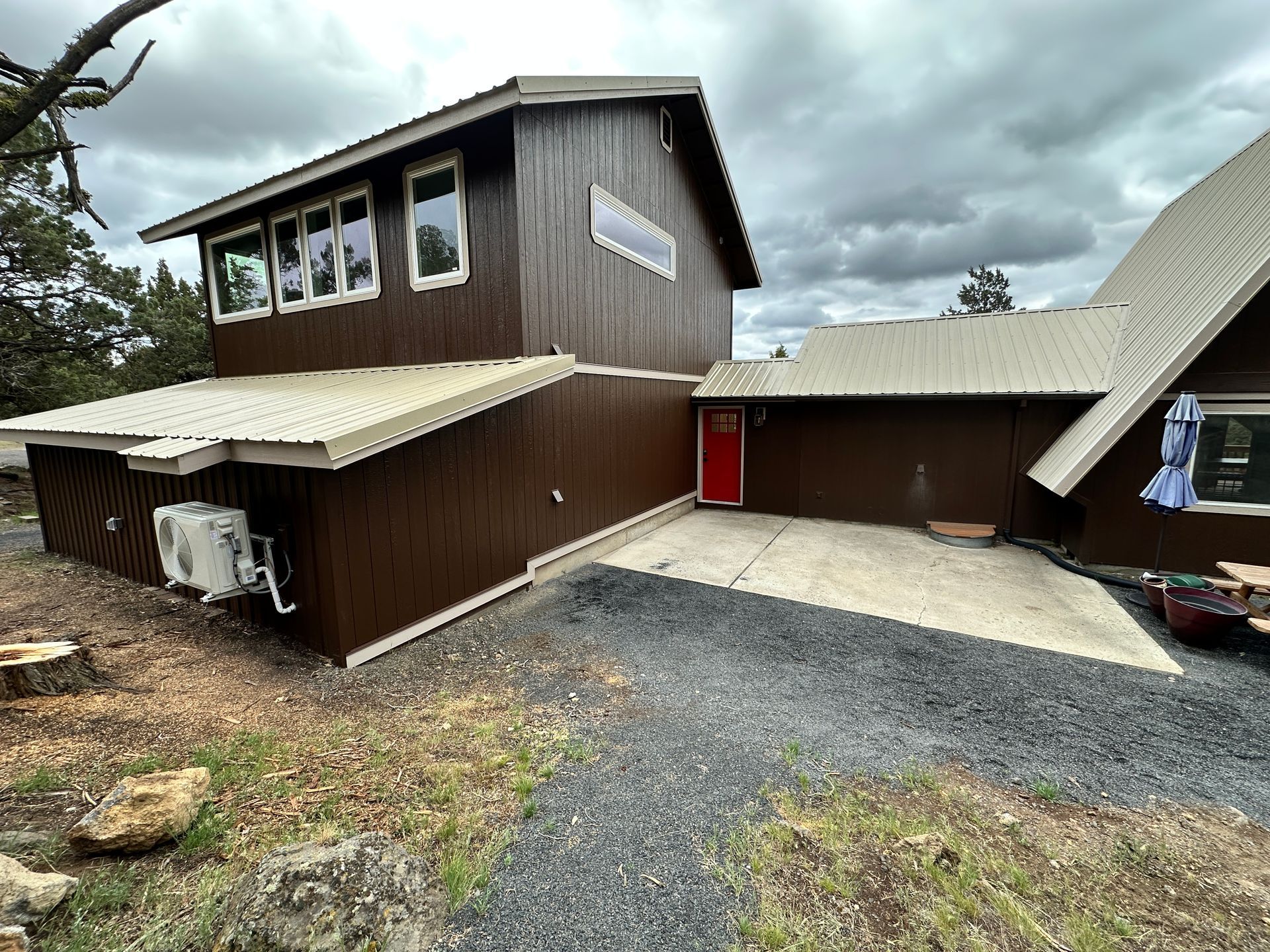 A large brown house with a lot of windows and a red door.
