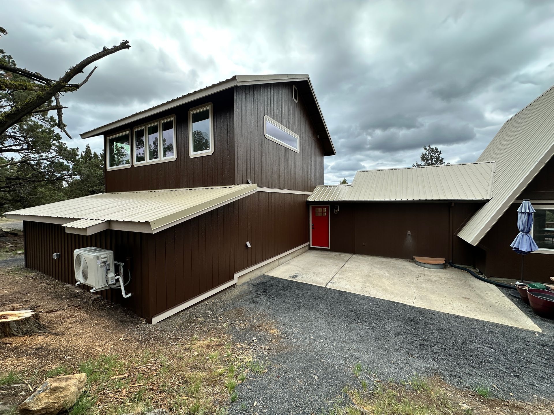 A large brown house with a white roof and a red door.