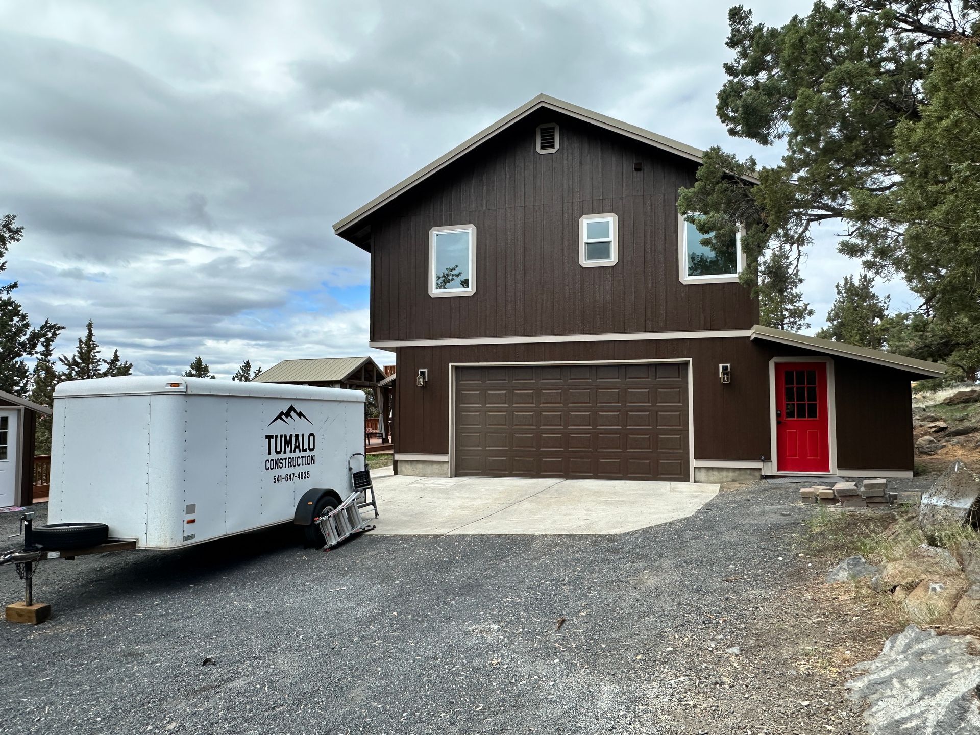 A large brown house with a white trailer parked in front of it.