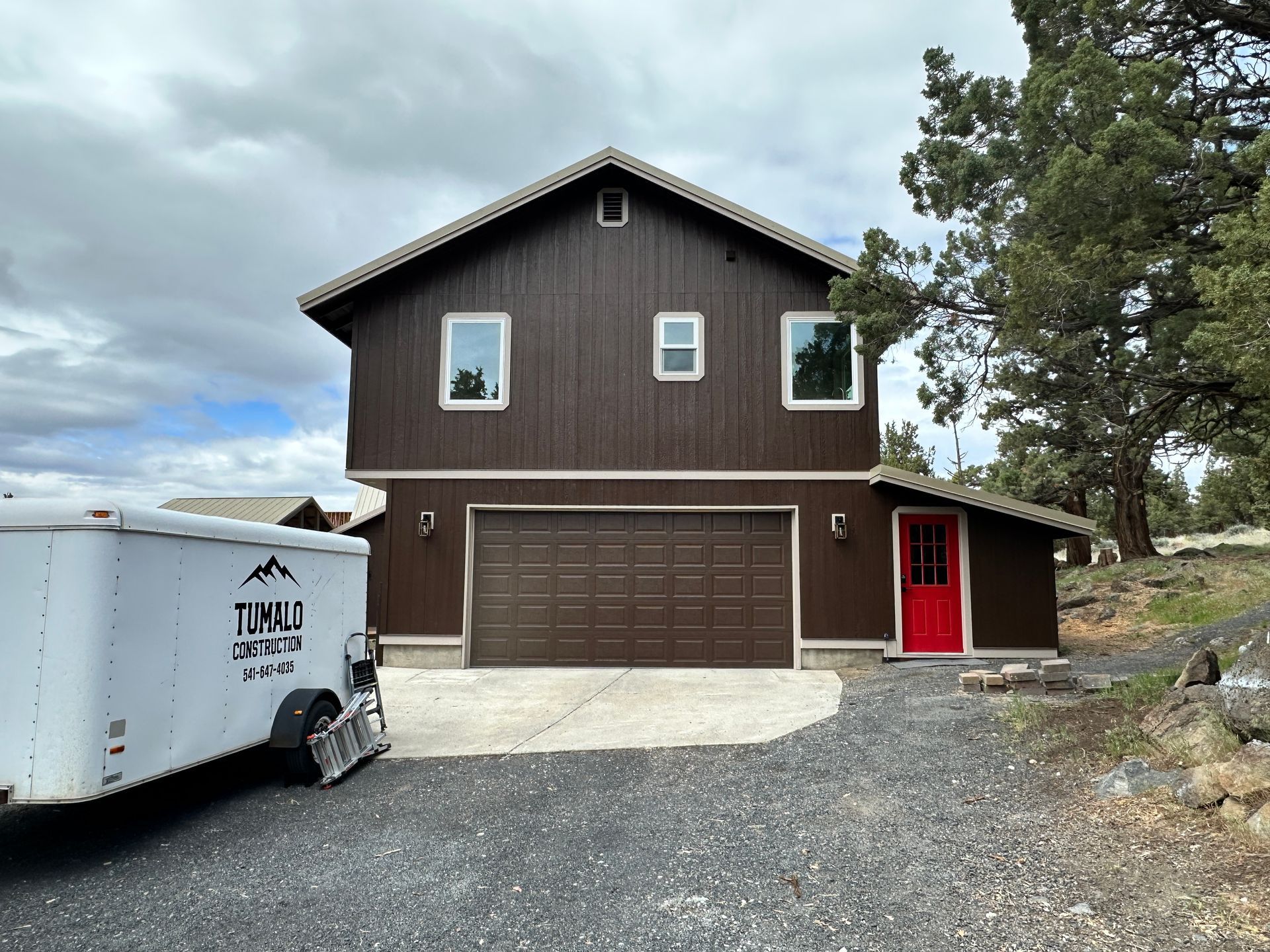 A large brown house with a white trailer parked in front of it.