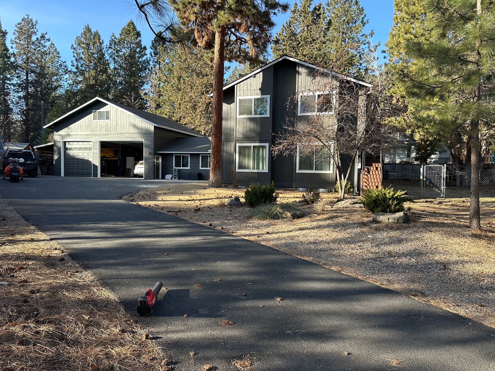 A large house with a garage and a driveway is surrounded by trees.