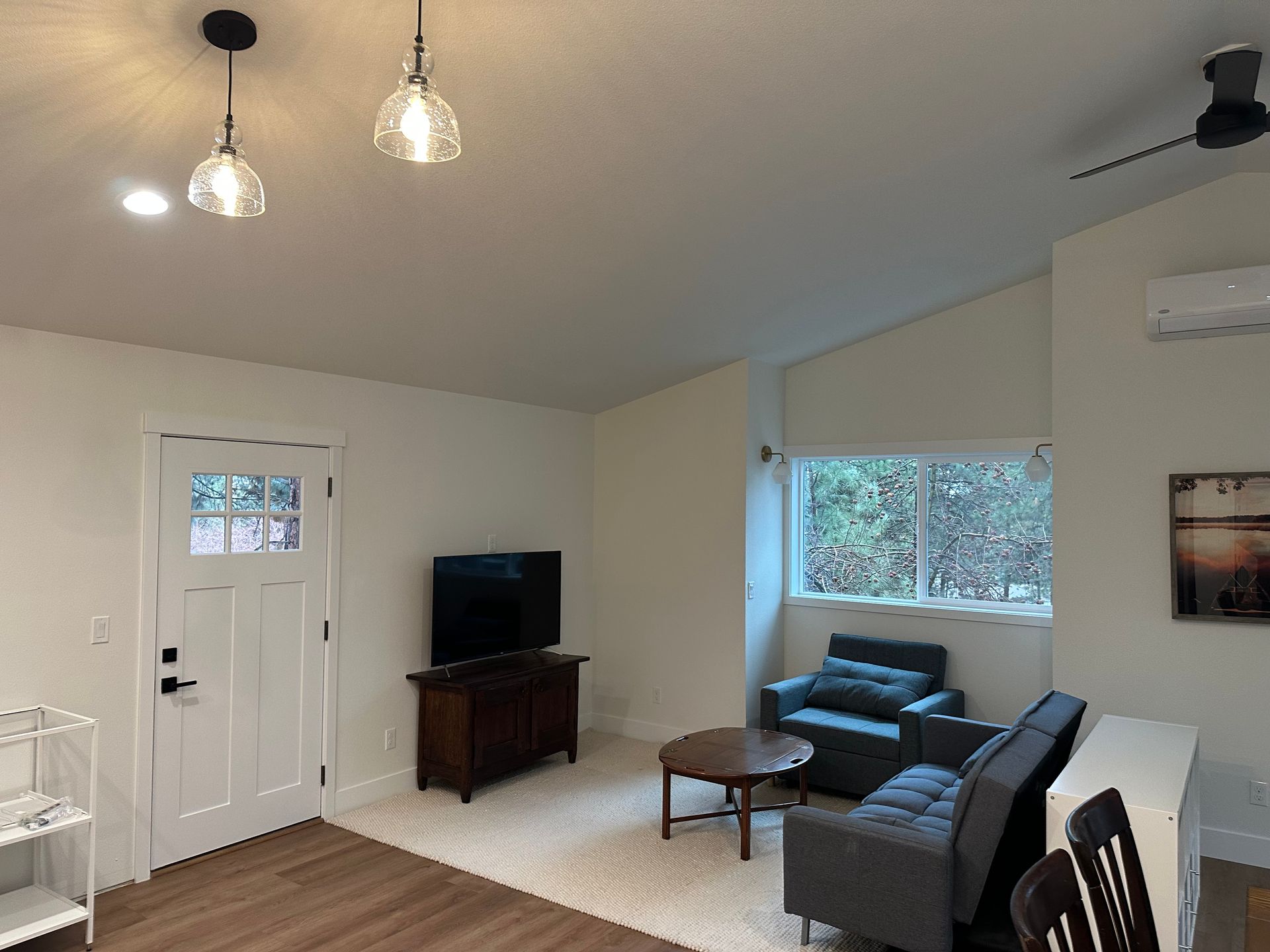 A living room with a couch , chair , table and television.