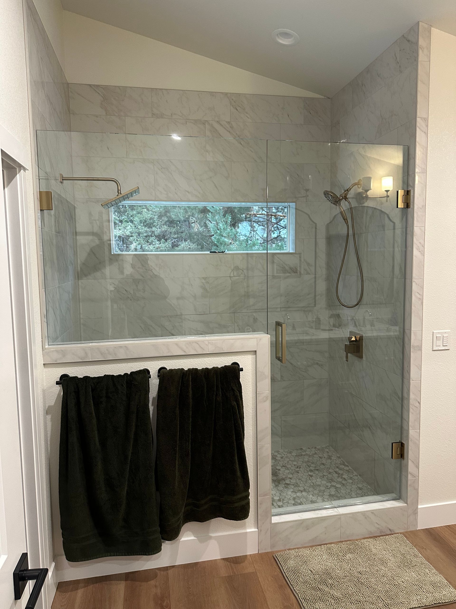 A bathroom with a walk in shower and a window.