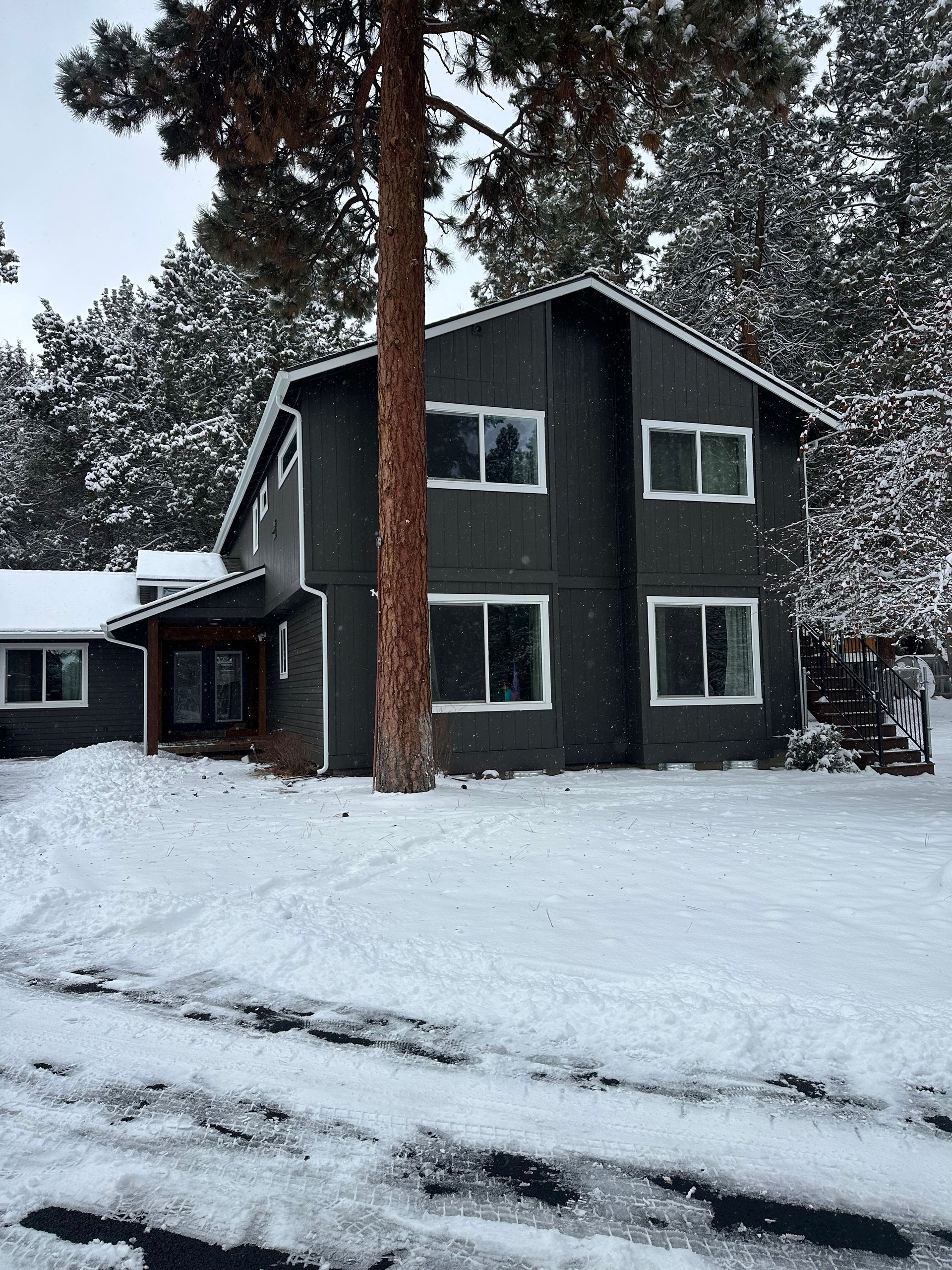 A house with a lot of windows is covered in snow