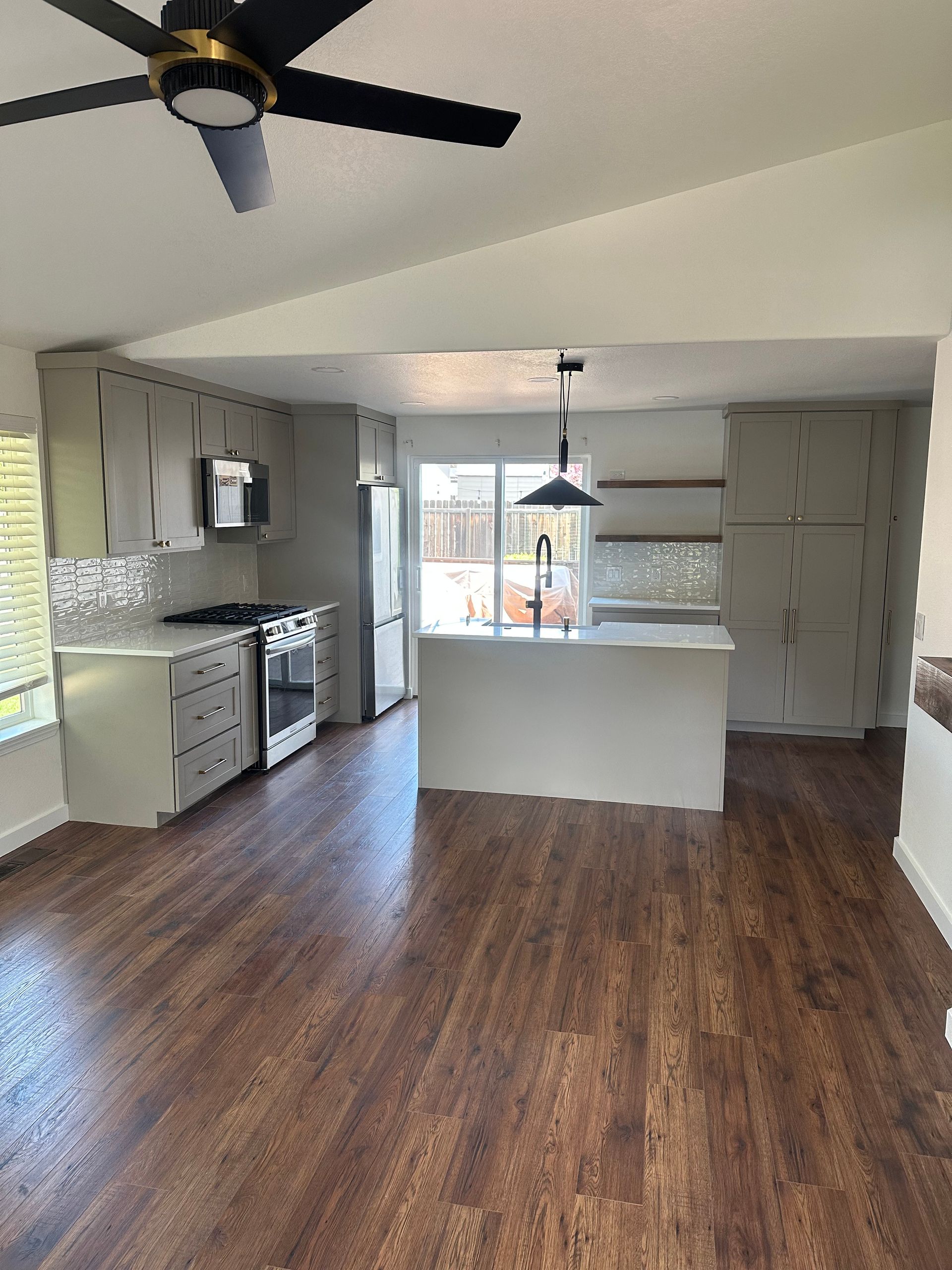 A kitchen with hardwood floors and a ceiling fan.
