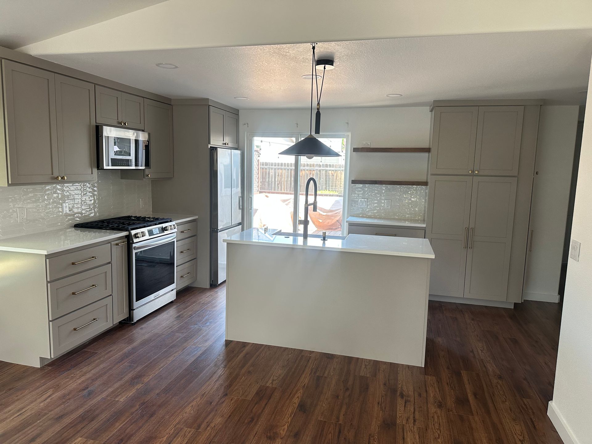 A kitchen with white cabinets , a stove , a refrigerator , and a sink.